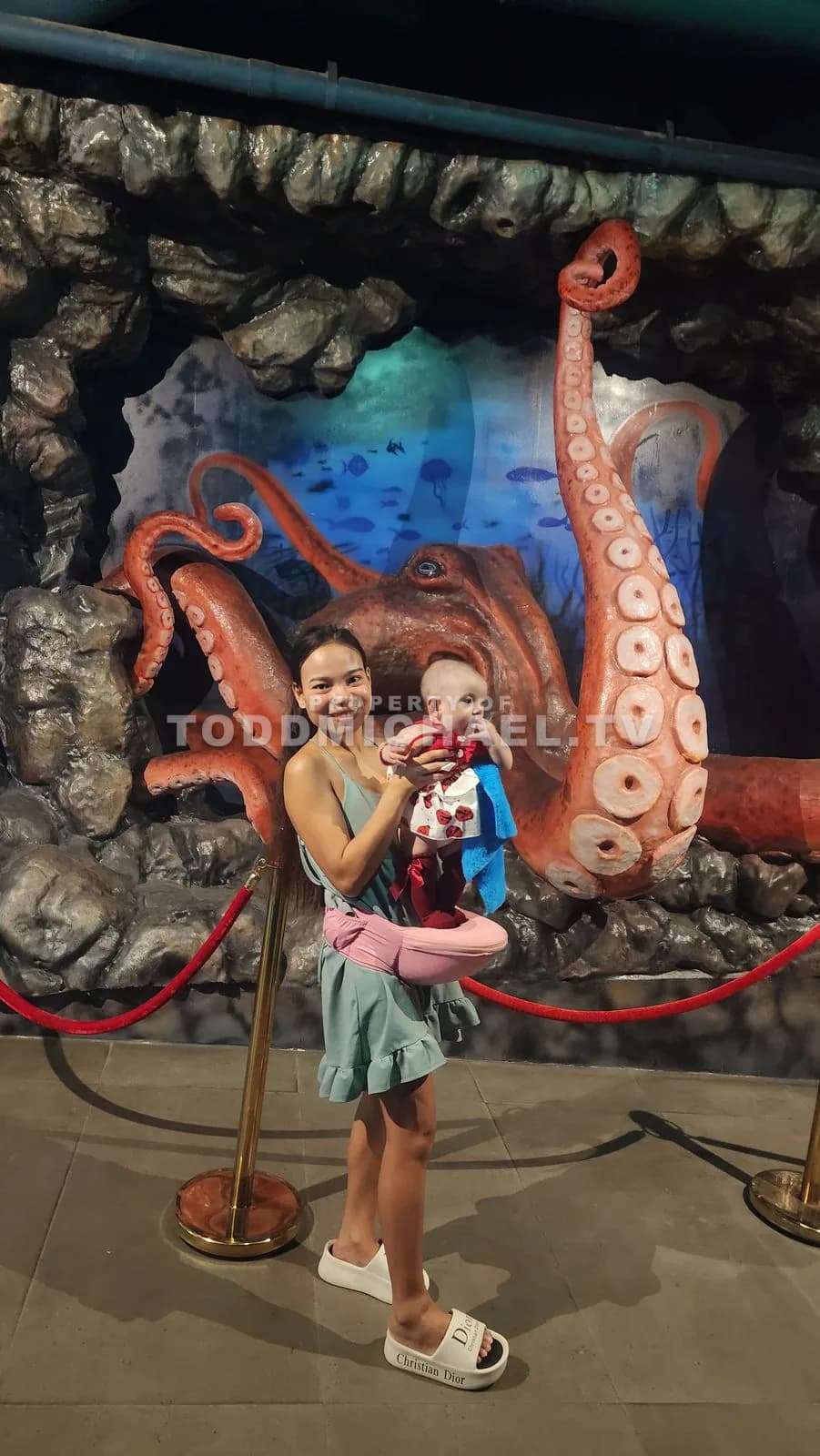 a family standing in front of a large octopus sculpture at an aquarium exhibit.