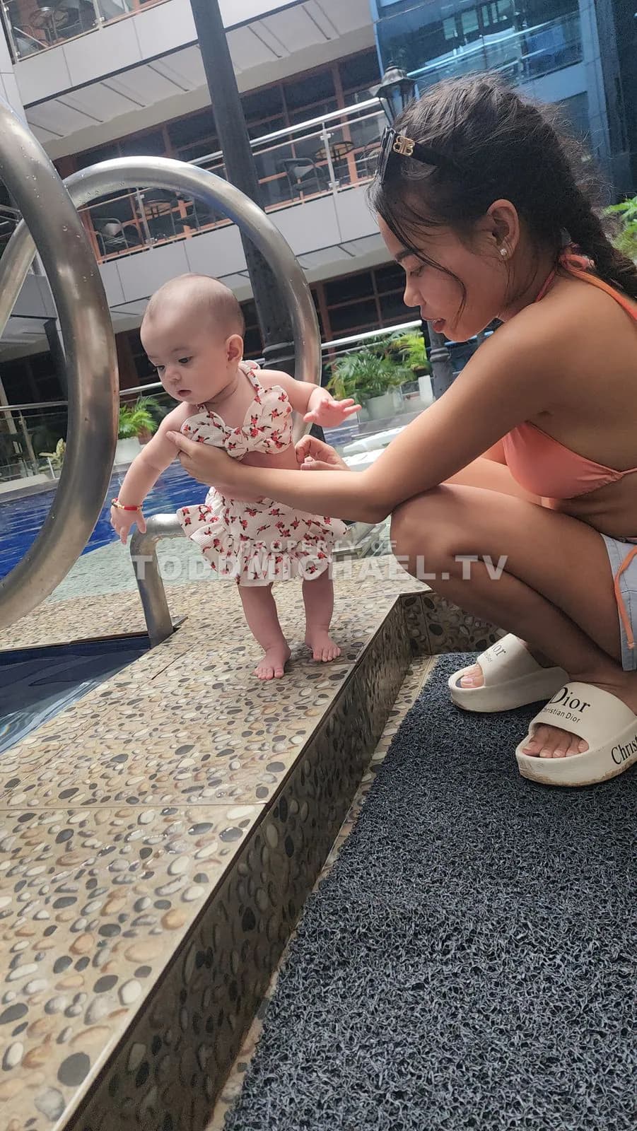 A woman and a baby interacting near a pool with metal handrails, captured at 10:17:26.