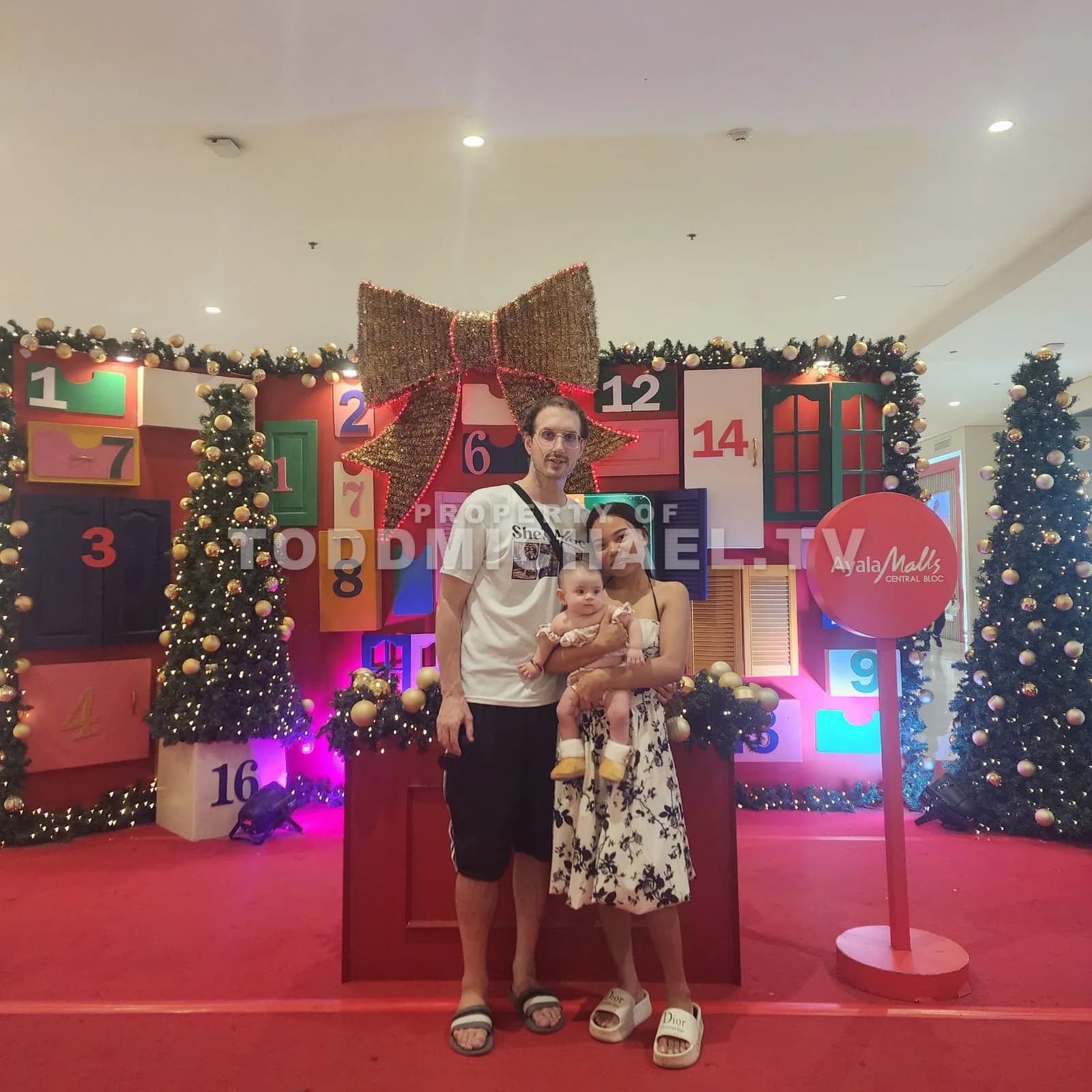a family standing together in front of Christmas decorations and numbers on the wall.