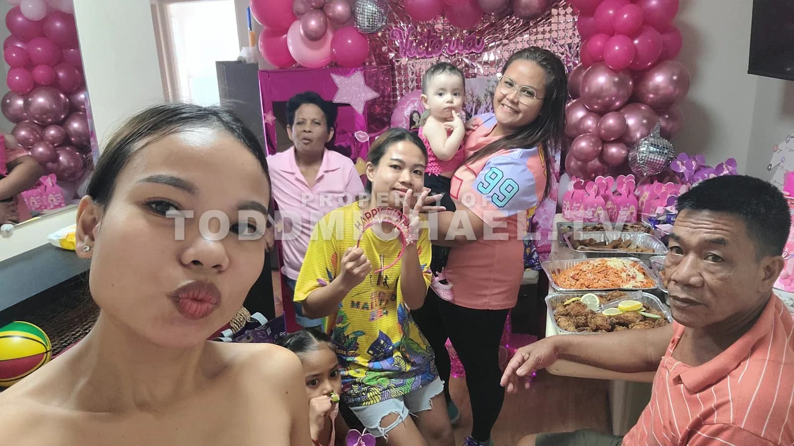 a family celebrating a child's birthday with pink decorations and balloons.