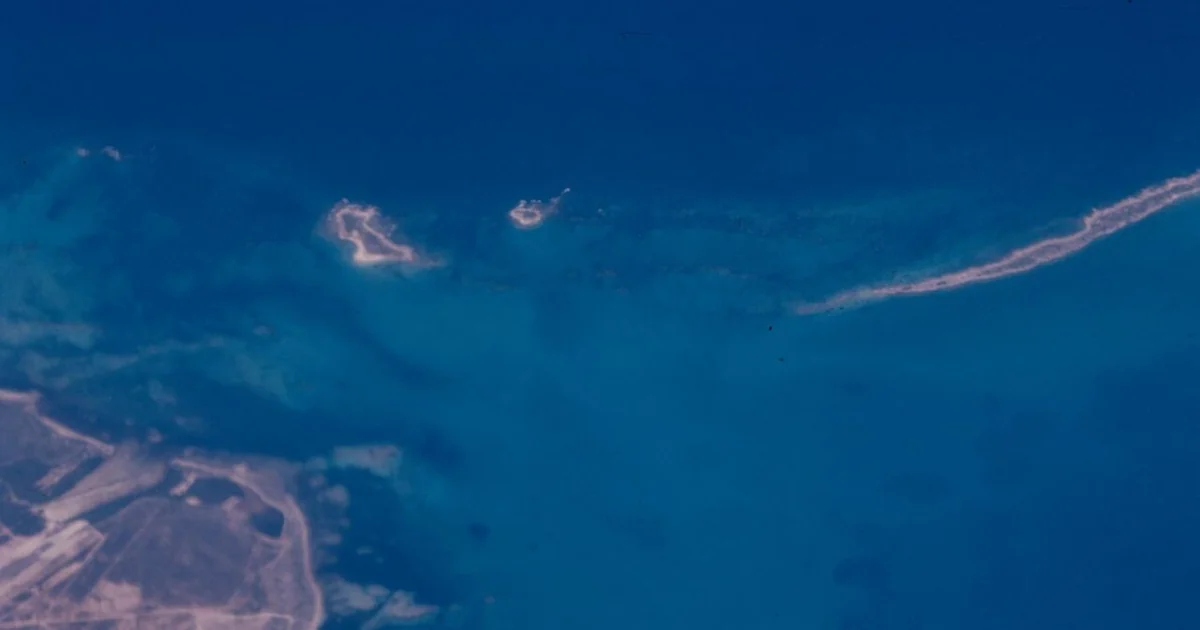 Aerial view, taken above clouds, of Florida's southern tip coastline over Fairchild Tropical Botanical Gardens in Coral Gable, Miami-Dade County. Two small islands and a long narrow island are seen to the right of the coastline.1 photograph